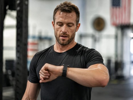 Man checking his fitness watch after a workout, representing tracked activity gains during a fitness challenge