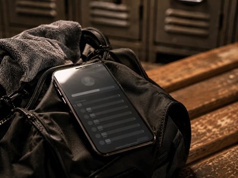 A close-up of a phone resting on a gym bag, screen showing a blank or ended tracker interface, symbolizing the moment the challenge structure simply stops existing.
